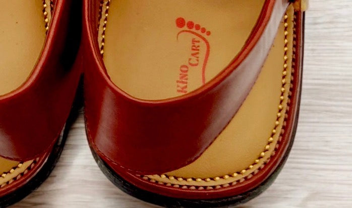 Brown leather sandal with visible stitching on a light background